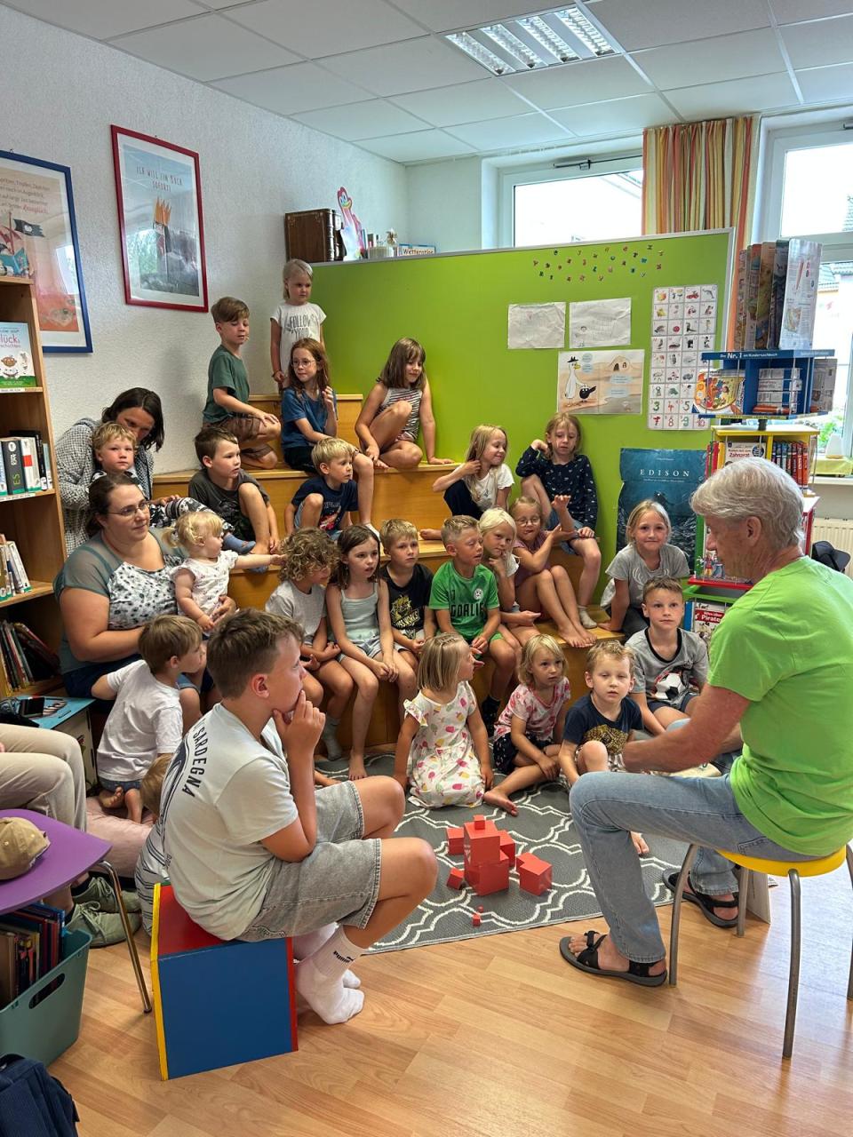 Viele Kinder sitzen auf einer Treppe und hören einem Mann zu