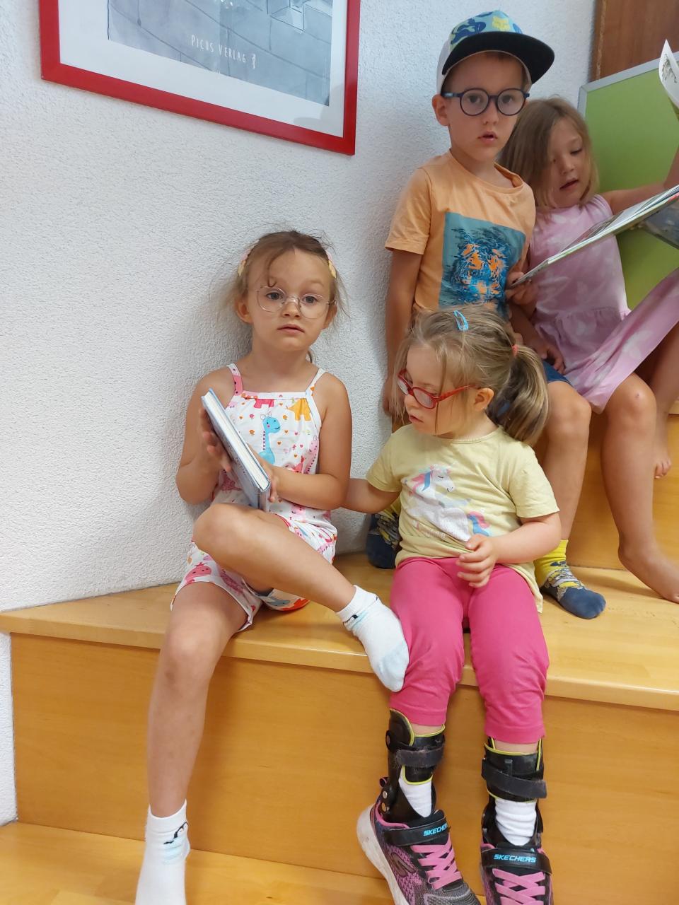 Vier Kinder sitzen mit Büchern zusammen