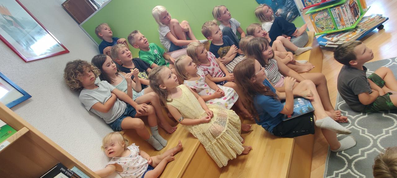 Kinder hören jemanden zu und sitzen auf einer Treppe