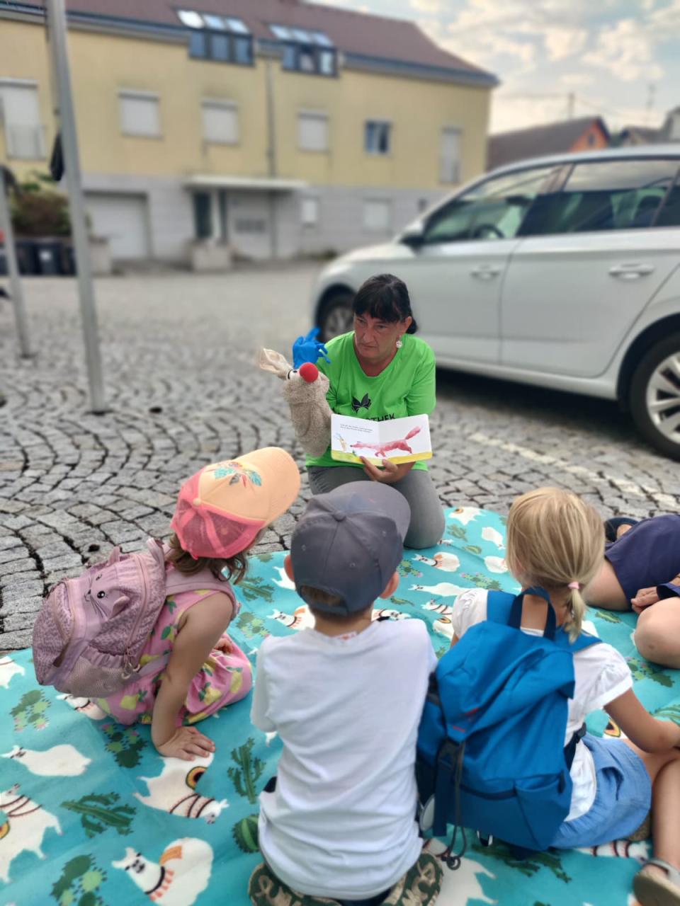Bilderbuch wird auf einem Parkplatz vorgelesen