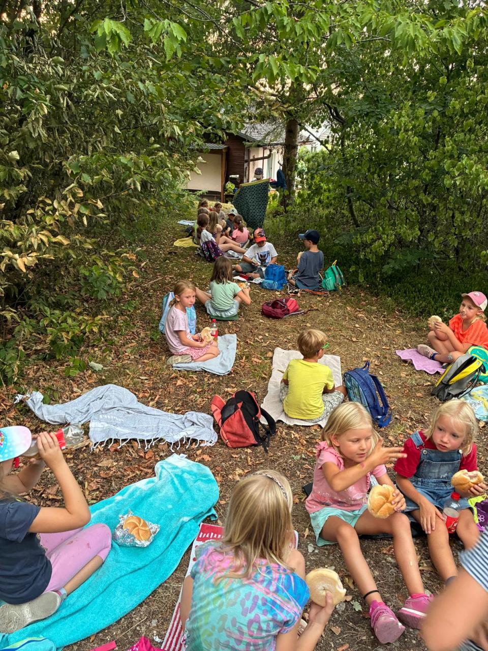 Kinder sitzen am Boden und jausnen