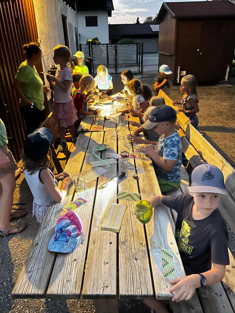 Kinder basteln im Freien an einem Holztisch
