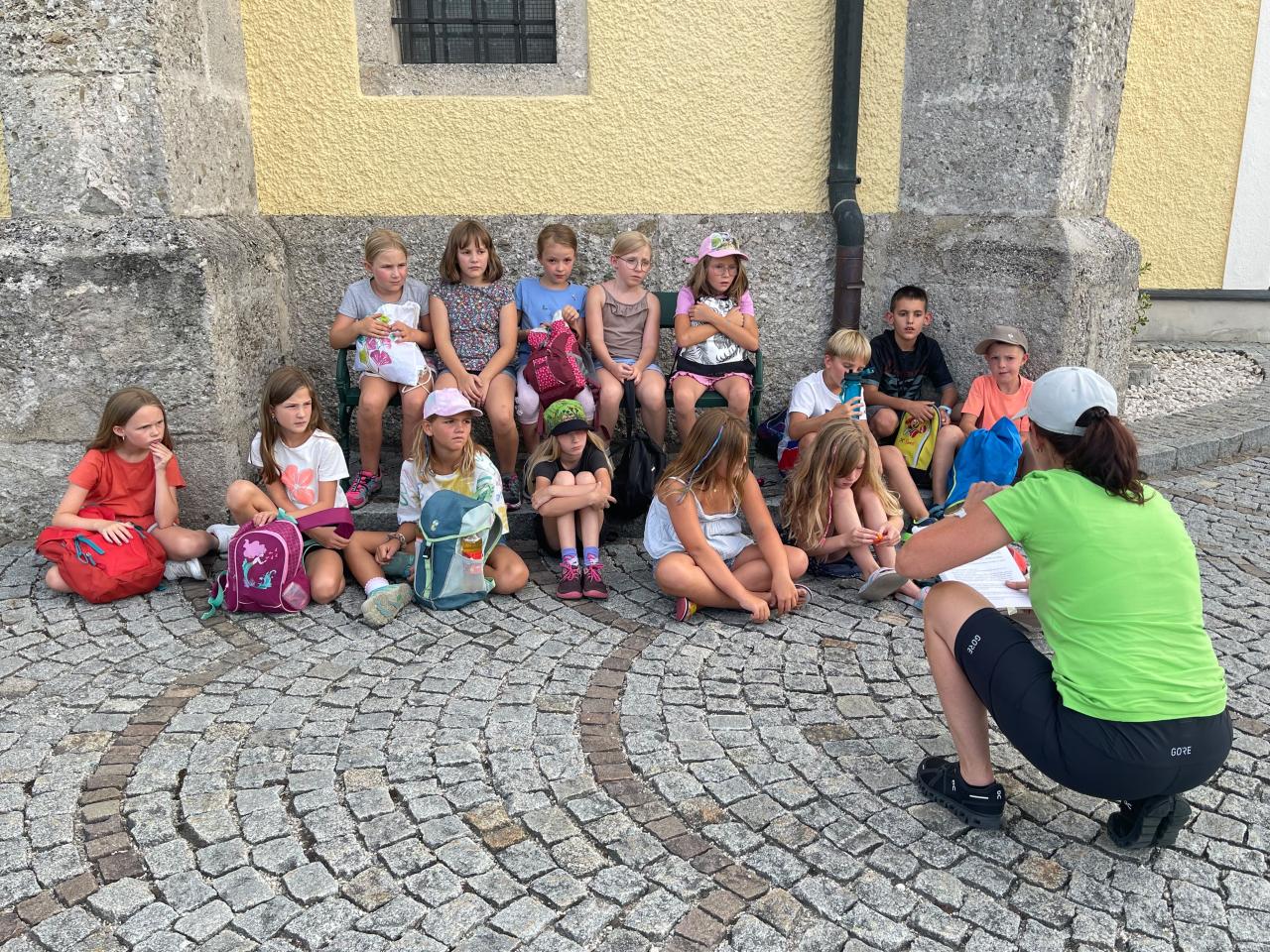 Kinder sitzen im Außenbereich der Kirche